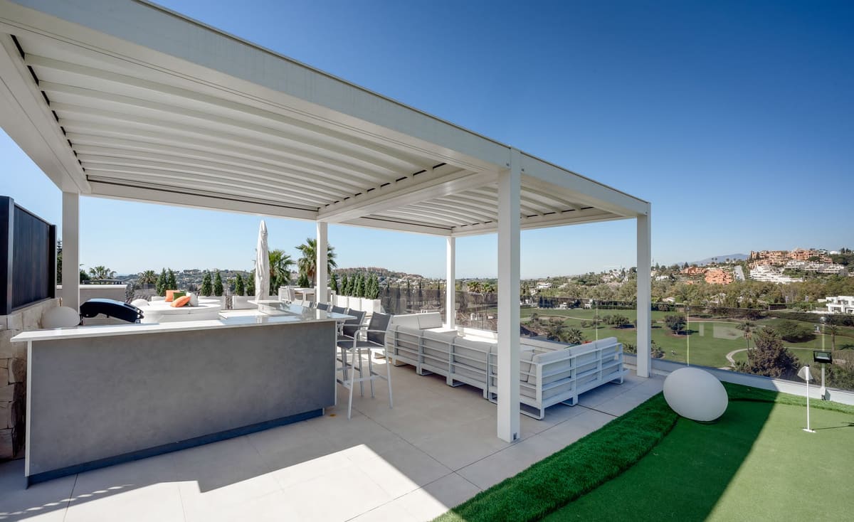 White louvred pergola over an outdoor kitchen on a rooftop terrace